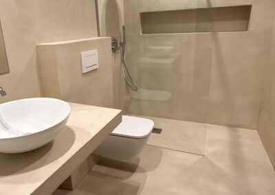 Baño de microcemento beige en Barcelona con ducha y lavabo | Grupo Renobe