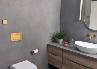 Baño moderno con microcemento gris en paredes y suelo, lavabo e inodoro suspendido